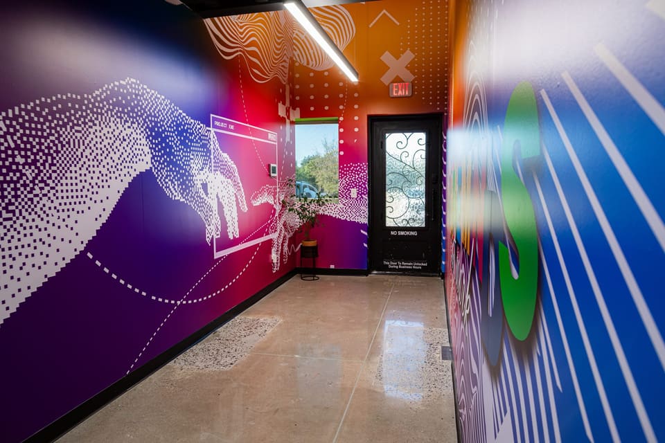Hallway wall print of a pixel-dot hand and flowing wave lines in purple, blue and orange