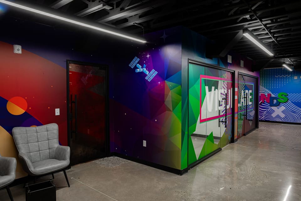 Reception corner with a gray chair, colorful geometric wall print and glass doors