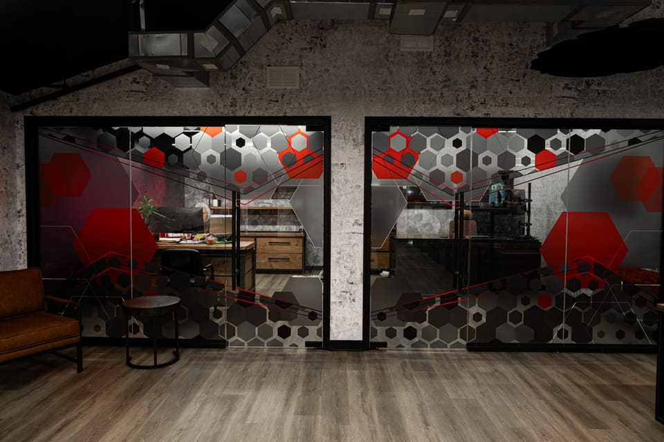 Two adjoining glass office fronts with a continuous hexagon frost and red accent pattern