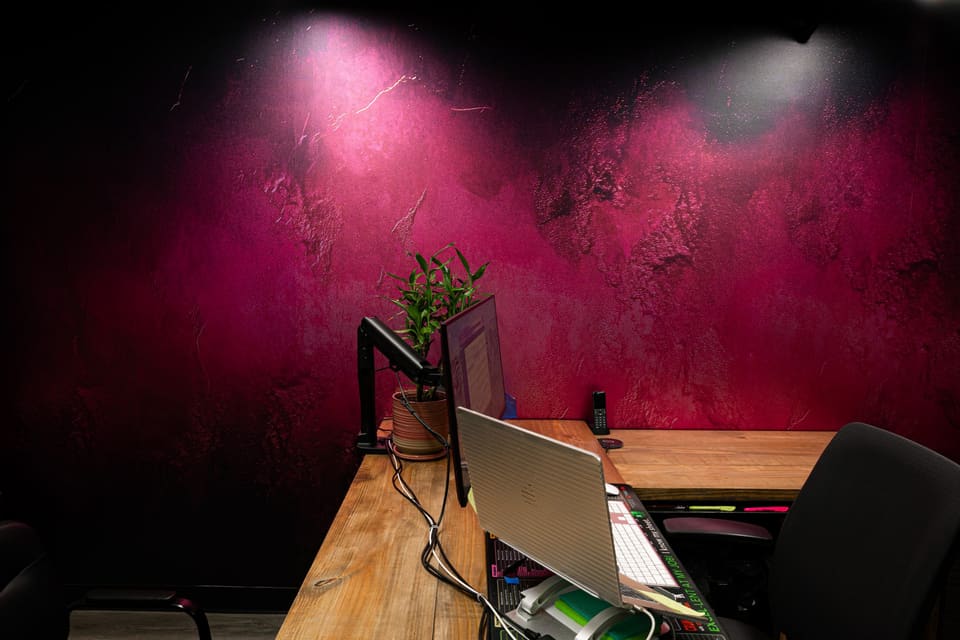 Workstation in front of a deep magenta textured wall finish
