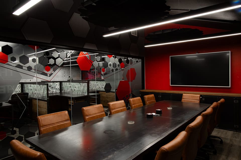 Conference room seen from the corner, with a patterned glass wall and red feature wall