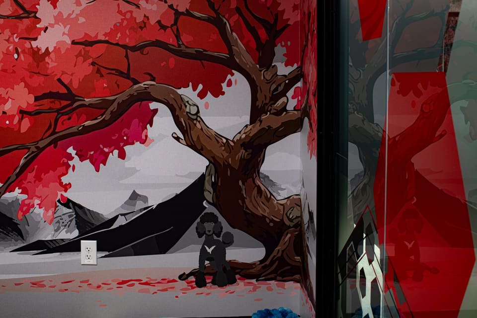 Mural of a red tree and mountains wrapping around a wall corner