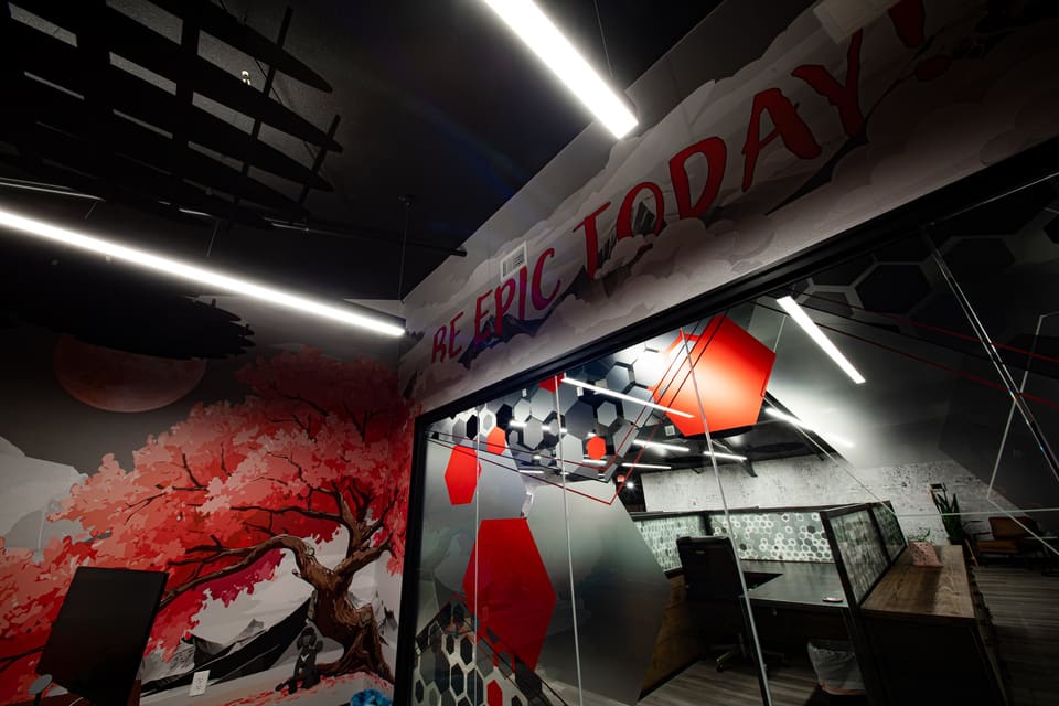 Red cherry-tree wall mural beside glass graphics in an office