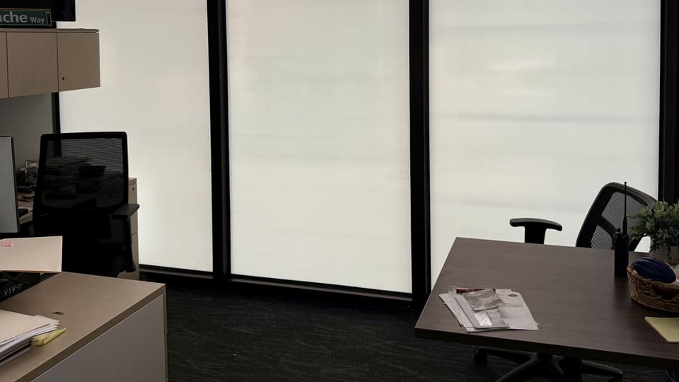 Finished office at a county government building in Albuquerque: a custom-printed frost band over 3M S2400 security film at screen height