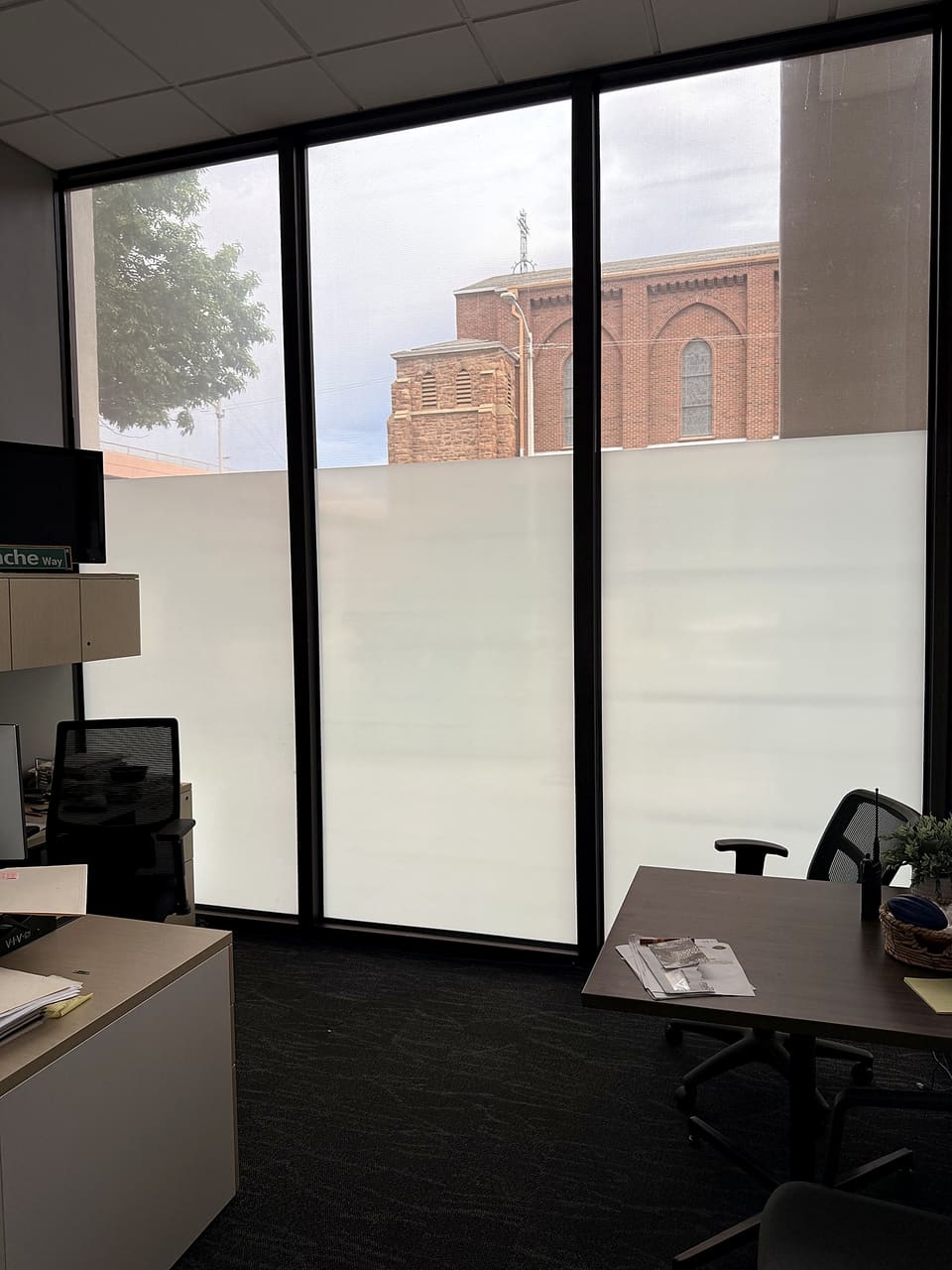 Finished office: a custom-printed frost privacy band over 3M S2400 security film at screen height, clear glass above and below