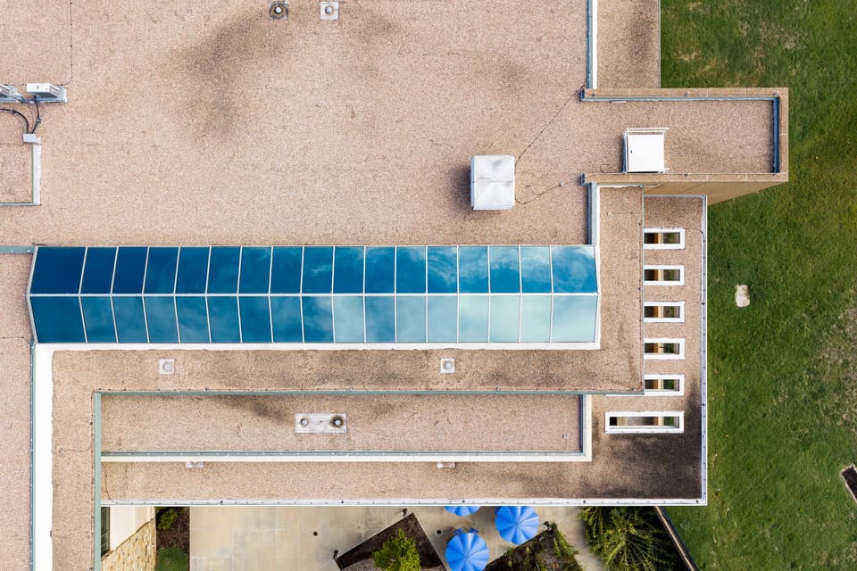 Aerial view of a low office building roof with a long blue-tinted skylight run