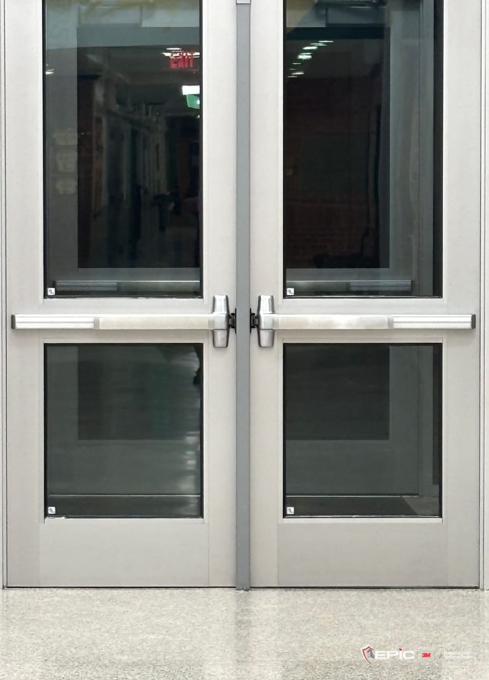 A pair of school entry doors with four filmed lites and push bars, an Epic badge in each lite